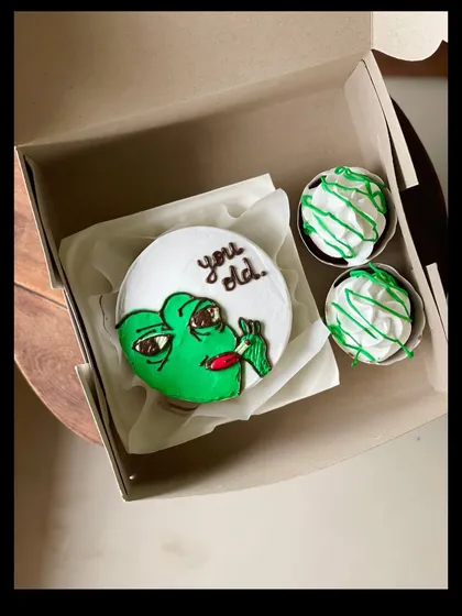 A funny birthday combo featuring the "You old" meme on a bento cake, accompanied by two cupcakes with matching green frosting. It's sure to get a laugh.