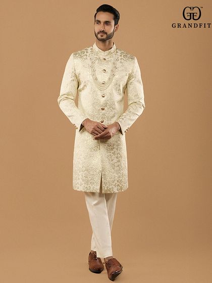 This ornate sherwani, paired with a multi-layered pearl mala, is designed for the groom who seeks a truly royal aesthetic. The intricate embroidery covers the entire garment for a luxurious finish.