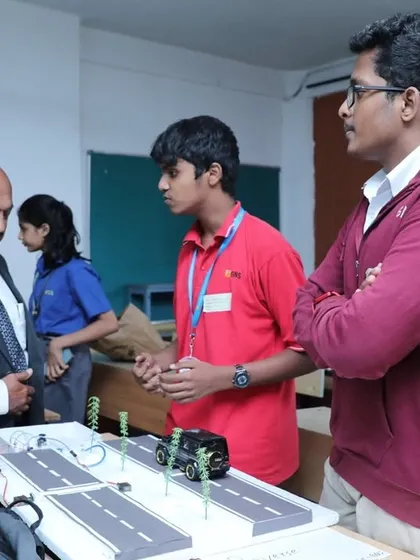 Here, our students explain their automated smart street model to a judge. This demonstrates how we encourage them to tackle real-world problems, like traffic management, and develop the technical and communication skills to present their solutions effectively.