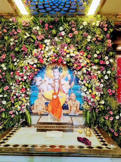 A lush floral backdrop created for the Sai Baba Mandir. We used a dense arrangement of mixed flowers and greenery to create a beautiful and serene frame around the central portrait of the deity.