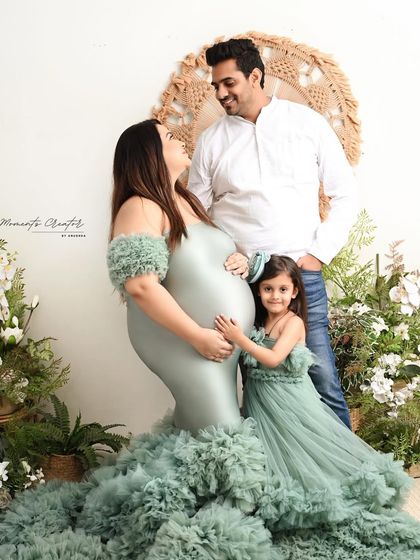A candid moment of love and connection. This expecting mother and her daughter share a sweet look, both dressed in flowing green gowns, creating a beautiful memory before the new baby arrives.