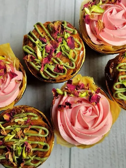 I enjoy creating unique fusion flavors, like these Baklava-inspired cupcakes for an Eid celebration. They combine the traditional taste of baklava with a modern cupcake format, decorated with pistachio drizzle, crushed nuts, and dried rose petals for an exquisite finish.