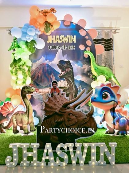 A dinosaur-themed birthday decoration designed for a home setting. We created a dramatic scene with a volcano backdrop, multiple large dinosaur cutouts, and light-up marquee letters spelling the birthday boy's name.