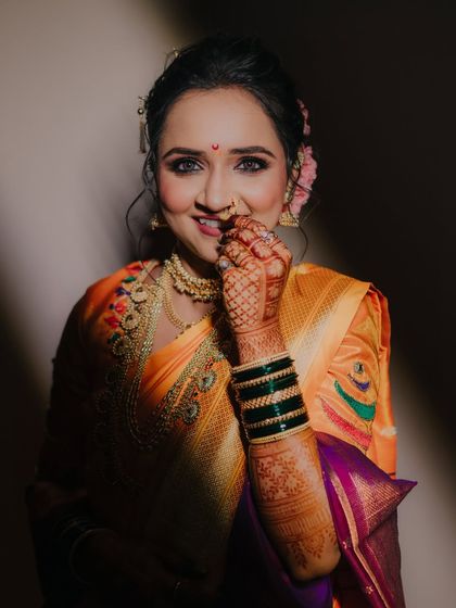 A playful and charming portrait of the bride, her hand gently touching her face, highlighted by a beautiful ray of light.