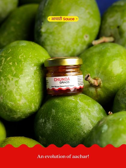 A mini jar of our Chunda Sauce resting on a bed of the raw mangoes we use to make it. We sun-age it for two weeks to develop its unique flavour.