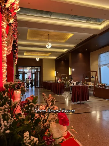A view from the entrance of the banquet hall, with floral arrangements in the foreground. It shows how guests are welcomed into the space where the elegant dining and buffet areas await.