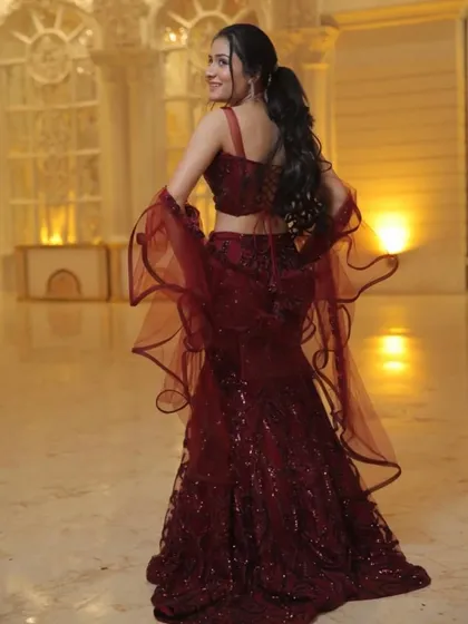 A back view of the maroon sequined mermaid lehenga, showing off the stylish cut and the flow of the ruffled dupatta.