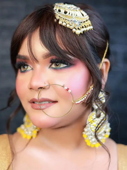 A close-up beauty shot focusing on the traditional headpiece, nose ring, and eye makeup.