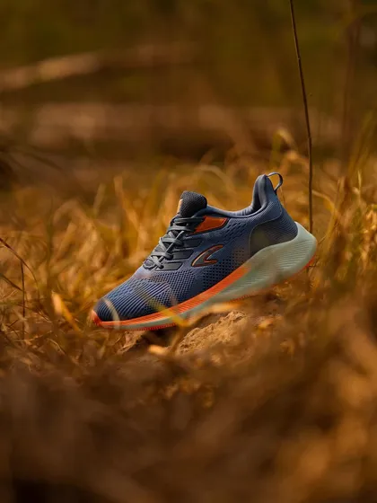 An outdoor shot of a running shoe in a field of dry grass. The shallow depth of field makes the shoe pop, while the natural setting emphasizes its use for outdoor activities.