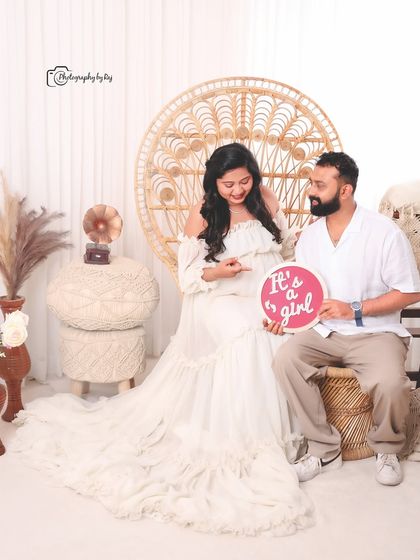 A happy gender reveal in our bohemian studio setup, with the couple holding a sign that says "It's a girl!".