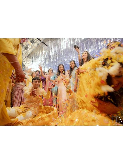 A Haldi ceremony in full swing. This wide shot captures the joyful chaos as friends and family shower the couple with flowers and turmeric, a perfect memory of a fun-filled event.