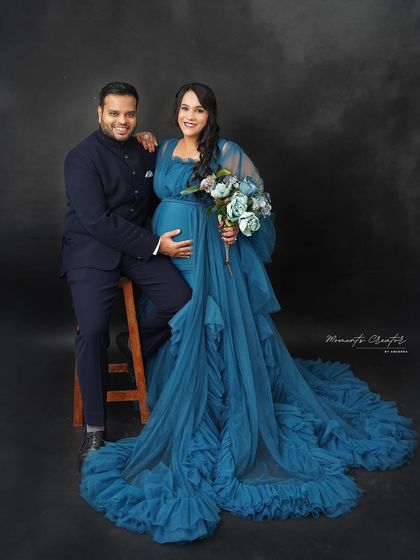 A sophisticated couple's portrait. The deep blue gown and the partner's matching navy suit create a coordinated and elegant look against a smoky black backdrop.
