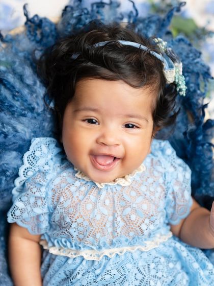 A big, happy smile from our "Blueberry" baby. This close-up shot in her blue lace dress is full of joy and personality.