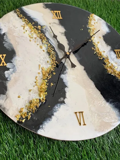 A bold and modern clock featuring black, white, and beige stripes with gold foil accents.