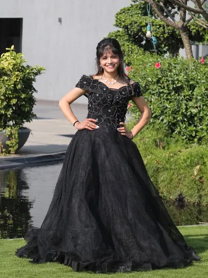 A classic black ball gown for a touch of timeless elegance. This off-shoulder dress with floral embroidery is perfect for a formal reception or cocktail party.
