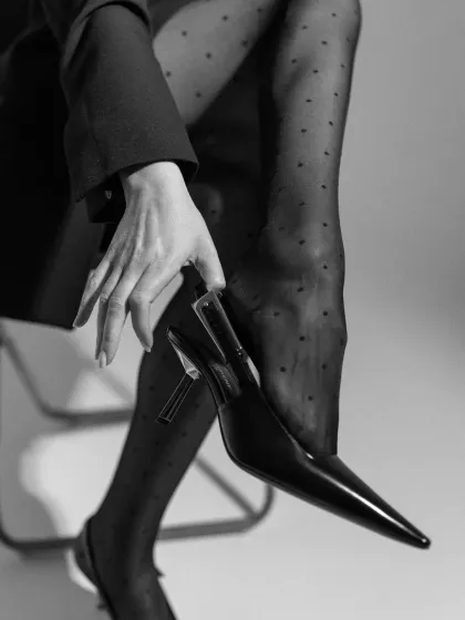 A black and white detail shot focusing on a pointed-toe slingback heel and polka-dot tights. This image highlights my ability to create sophisticated, accessory-focused editorial content.