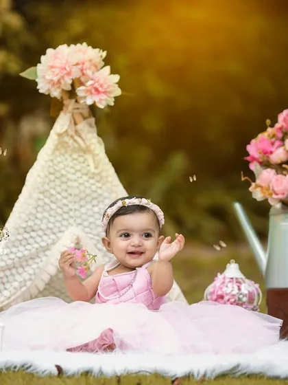 Let your little one shine in the great outdoors. We create beautiful, naturally lit portraits in picturesque settings, like this whimsical teepee setup that perfectly frames a happy one-year-old's smile.