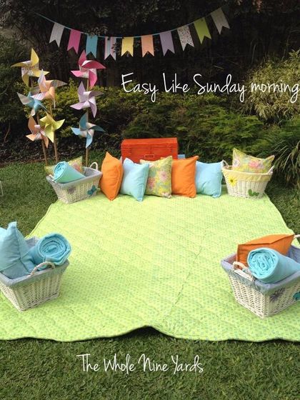 "Easy like Sunday morning." A simple and inviting picnic spot with comfortable blankets and cushions, perfect for a relaxed celebration in the sun.