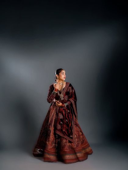A full-length studio portrait where the magnificent lehenga is given space to breathe. The dramatic, focused lighting creates a sense of regal solitude and timeless grace.