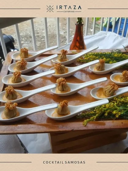 Cocktail Samosas, elegantly served on individual porcelain spoons with a swirl of sauce. This presentation is perfect for a sophisticated cocktail party where guests are mingling.