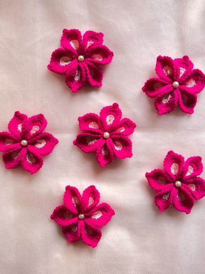A set of six beautiful magenta-colored flowers, each adorned with a small pearl. These can be used for any kind of craft or decoration.