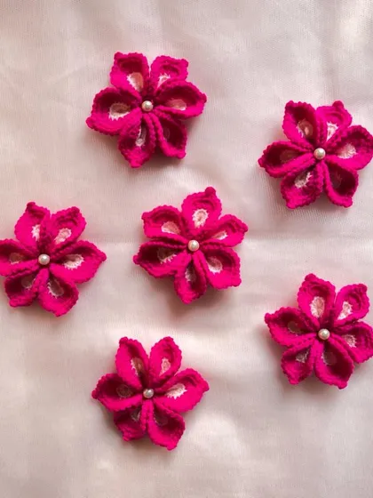 A set of six beautiful magenta-colored flowers, each adorned with a small pearl. These can be used for any kind of craft or decoration.