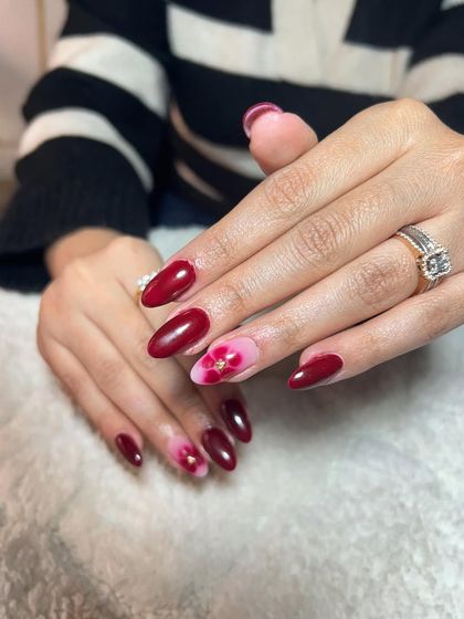 A lovely design with a deep red base and delicate blooming gel flowers on the accent nails. This technique creates a soft, watercolor-like effect.