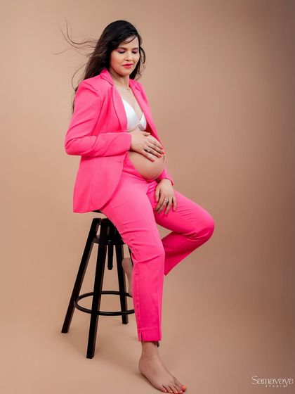 The wind in her hair adds a touch of dynamic energy to this modern, seated portrait. The pink suit is a bold and fashionable choice.