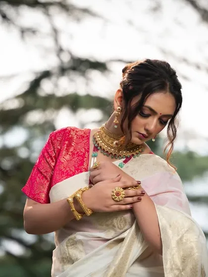 An artistic shot where the model is looking down at her hands, highlighting the traditional gold bangles and rings.