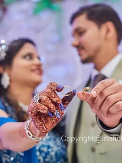 A creative ring shot where the couple holds their rings in the foreground, with their faces softly blurred in the background. This artistic composition puts the focus on the commitment they've made.