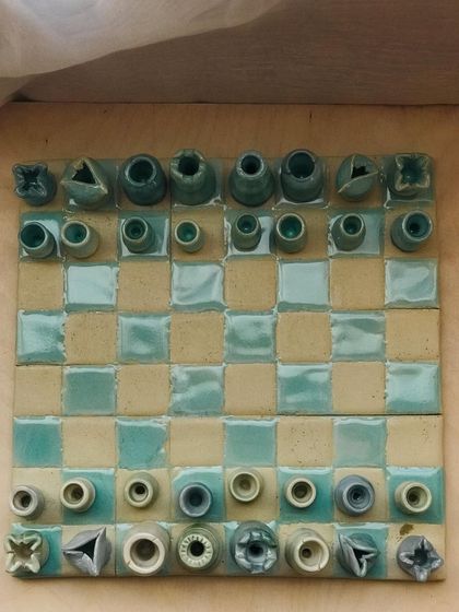 A top-down view of the "Cocoa Clash" chess set. The pieces are all uniquely shaped and glazed, making each set a one-of-a-kind work of art.