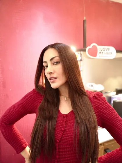 A close-up of the beautiful, smooth results after her treatment. The hair is healthy, shiny, and reflects the light beautifully, seen here inside the salon against a vibrant backdrop.