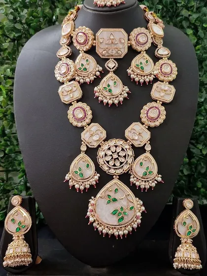 A unique and artistic bridal set featuring beautiful hand-painted enamel work with green leaves on a pearlescent base, surrounded by kundan stones.