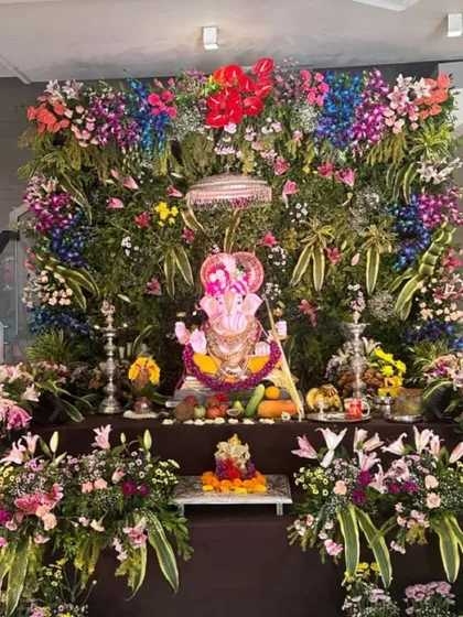 An explosion of color. This grand Ganpati mandap features a dense wall of fresh, colorful flowers, creating a stunning and joyful garden to welcome Bappa.