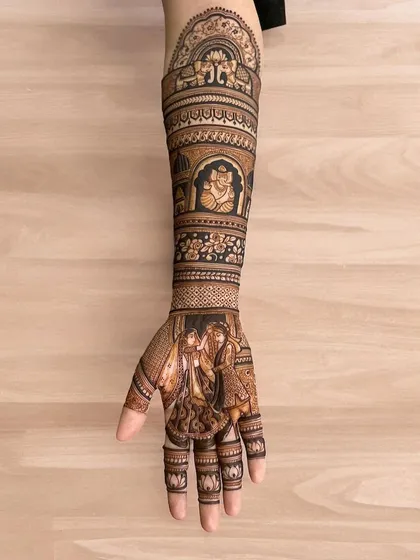 A single full-arm design showcasing a varmala scene on the palm and a Ganesha figure on the arm.