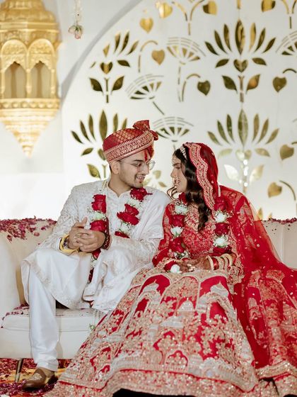 The couple seated on their elegant white and gold stage, sharing a quiet moment during their traditional wedding ceremony.
