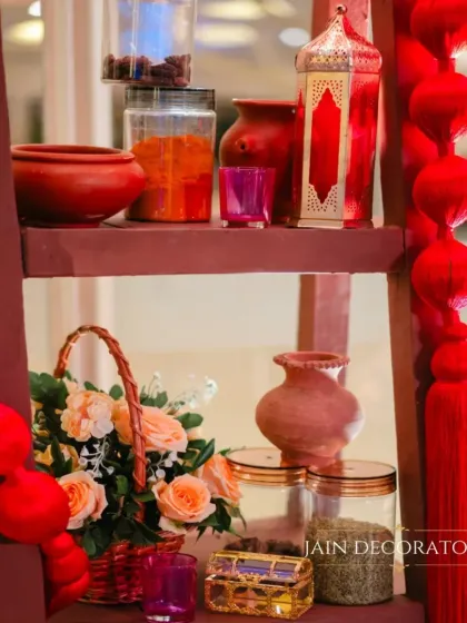 Details that add to the theme. This shelf is styled with red tassels, lanterns, and floral arrangements, reinforcing the crimson and gold color story of the event.