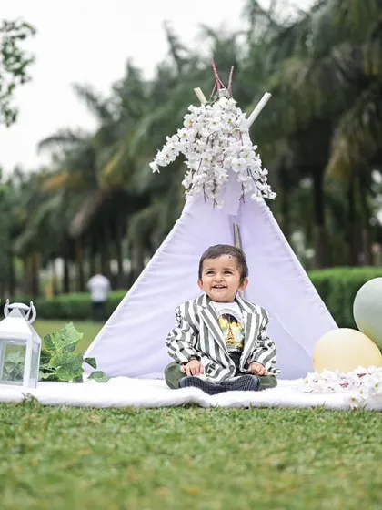 The birthday boy looking sharp in his 'Boss Baby' style outfit during his outdoor shoot. The teepee is decorated with white flowers for a touch of elegance.