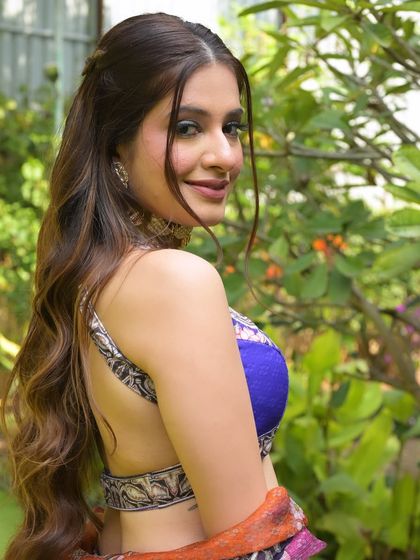 A happy, over-the-shoulder shot showcasing the backless design of the blouse and the soft, wavy hairstyle.