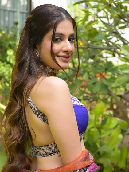 A happy, over-the-shoulder shot showcasing the backless design of the blouse and the soft, wavy hairstyle.