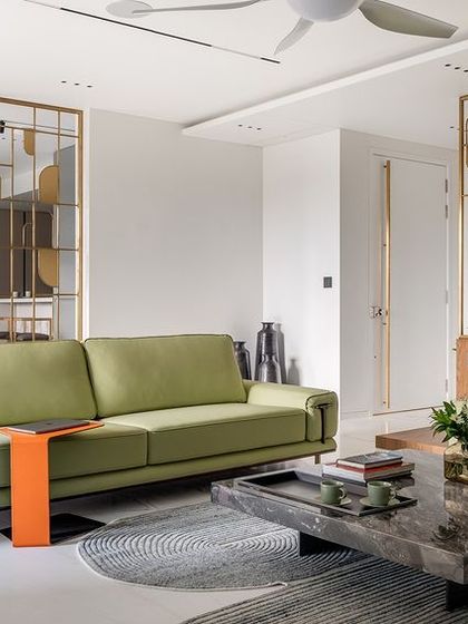 A wide view of the formal living room at Park West, where a vibrant green sofa adds a refreshing pop of color. The custom brass screen acts as a beautiful, porous boundary, defining the space while maintaining a connection to the adjacent dining area.
