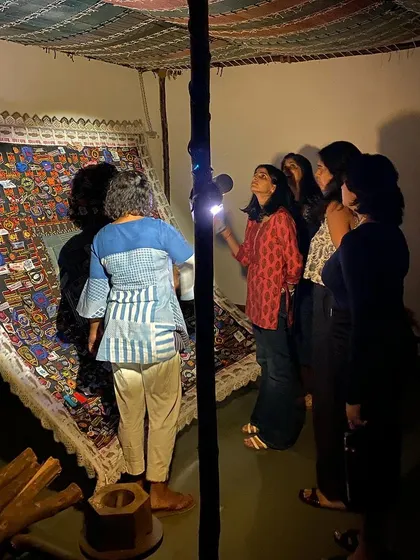 The team from MAP Bangalore visiting the 'WEAVING LIGHT' exhibition, using flashlights to explore the details of the intricate textile works in the darkened gallery.