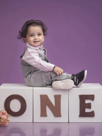 A classic first birthday pose, with the baby boy sitting comfortably on top of the 'ONE' blocks. This clean and simple setup is perfect for timeless milestone photos.