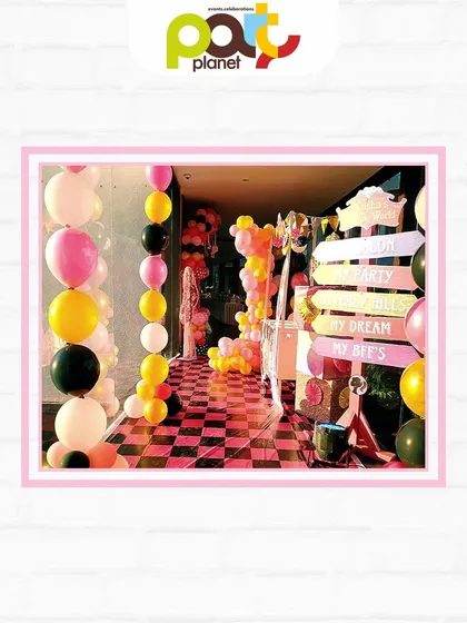 A glamorous entrance for a Barbie party, with a pink and black checkered floor, balloon garlands, and a signpost to "My Dream Hills."