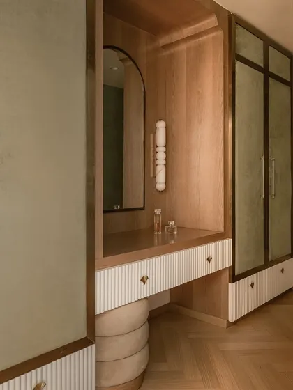 The walk-in closet and vanity area, designed with warm oak, ribbed white panels, and sage green velvet accents. The space is a refined mix of elegance and playfulness.