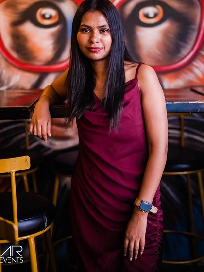 A guest in a maroon velvet dress, posing against the graffiti wall.