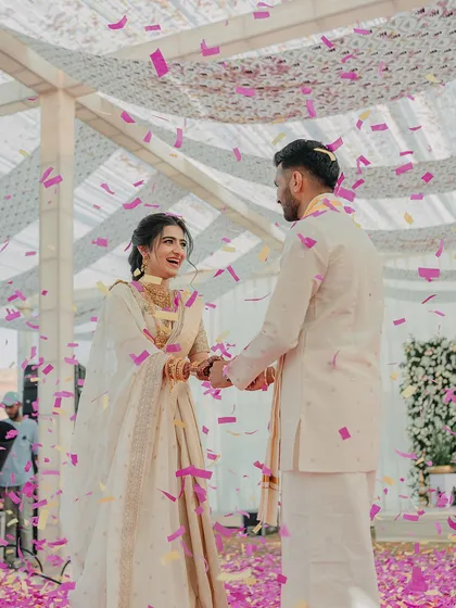 A moment of pure joy during the South Indian ceremony, with the couple surrounded by family and showered in confetti. The traditional white and gold attire looks stunning.
