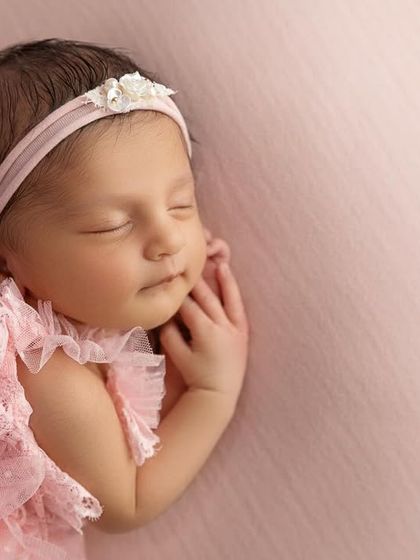 A beautiful close up focusing on the baby's face and hands, with the frilly details of her dress creating a soft frame.