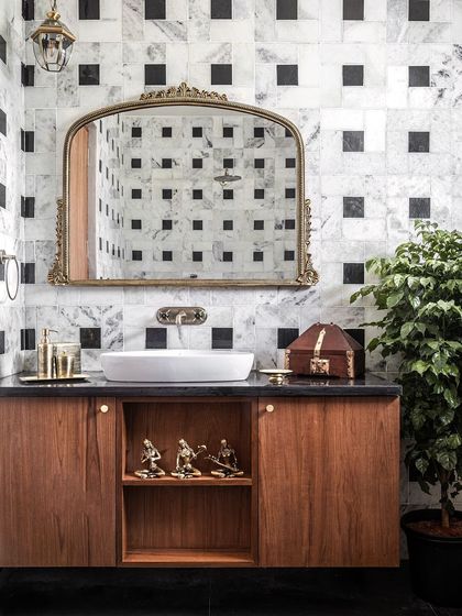 For the master bathroom, we wanted timeless elegance. We chose a classic combination of white marble and black granite in a dual-tone pattern, juxtaposed with brass accessories and rich teak cabinetry for a regal and classic feel.