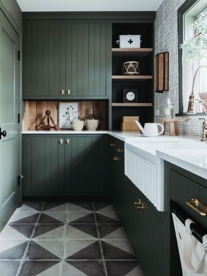 We create kitchens that reflect your personality. This design uses a deep olive green for the cabinets, paired with a classic farmhouse sink and geometric floor tiles for a rustic yet modern feel.